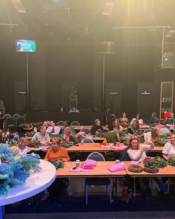 A large group making wreaths at an event venue