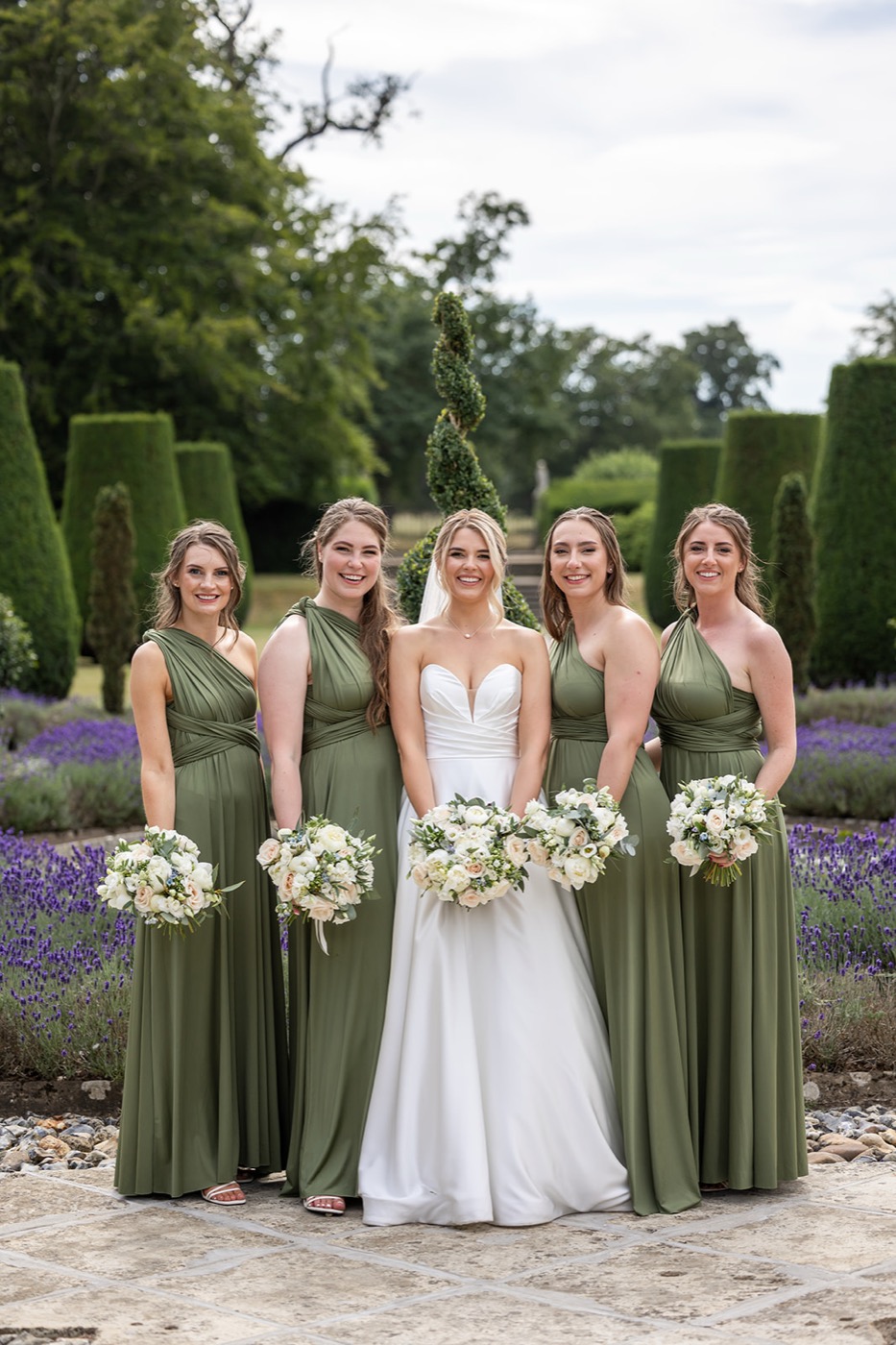 Bride and bridesmaids in sage green holding white and green bouquets