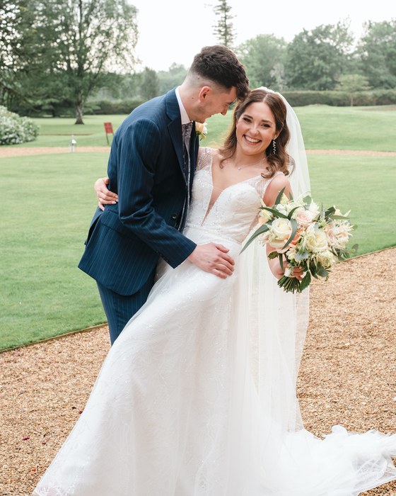 Couple on a lawn with the bride’s bouquet