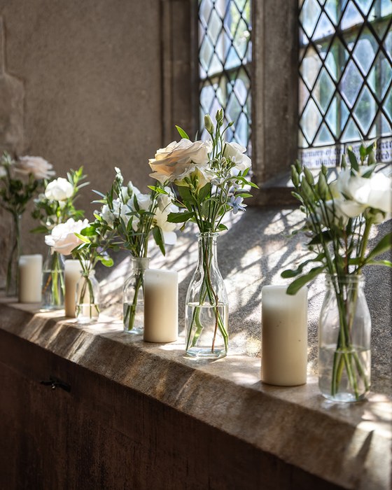 Window ledge arrangements in bud vases with candles