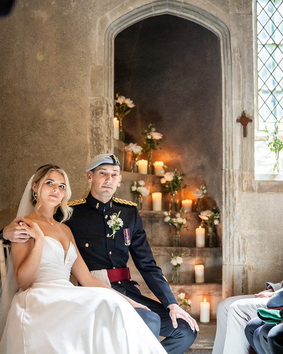 Couple seated beside candles and flowers in a church