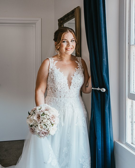 Bride by a window with a pastel bouquet