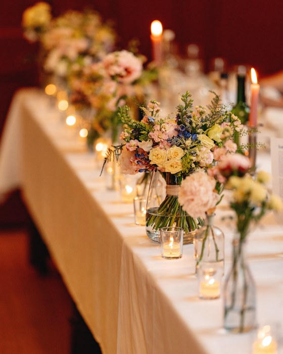 Long reception table dressed with low flowers and candlelight